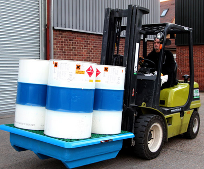 A man lifting drums on a plastic pallet